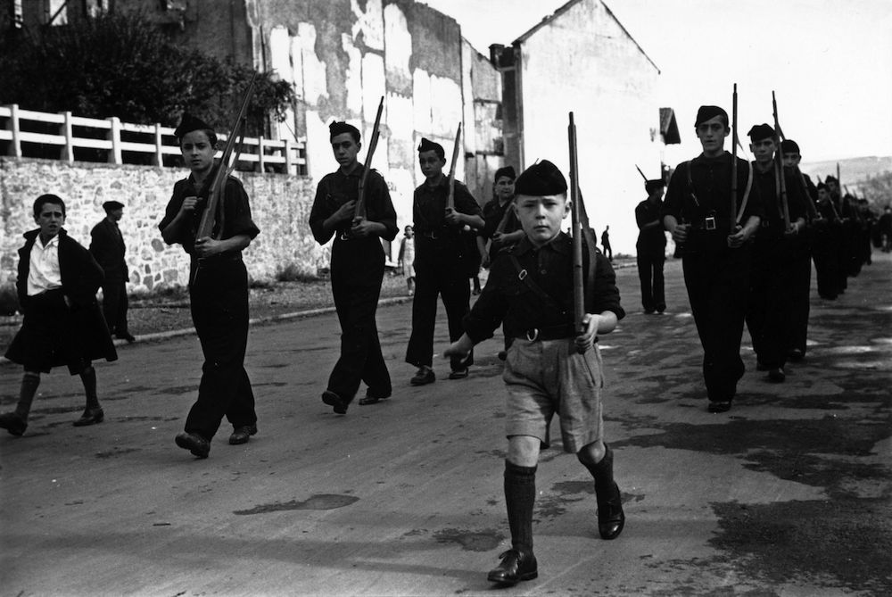 13th November 1936: A youth parade of Spanish schoolchildren makes its way along the road wearing the black shirts of the Fascists and carrying dummy rifles. Their home of Irun has been taken over by Rebel troops during the Spanish Civil War, and they have been converted to the Fascist cause. (Photo by Maeers/Fox Photos/Getty Images)