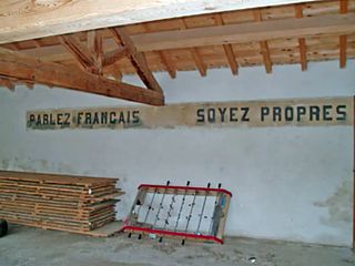"Speak Francais, Be Clean" painted on a school wall, photo wikipedia